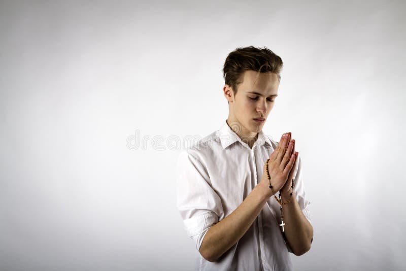 Young man is praying with rosary beads