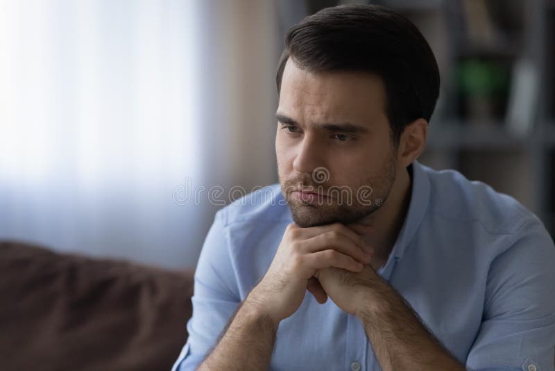 Young man put chin on hands lost in bad thoughts