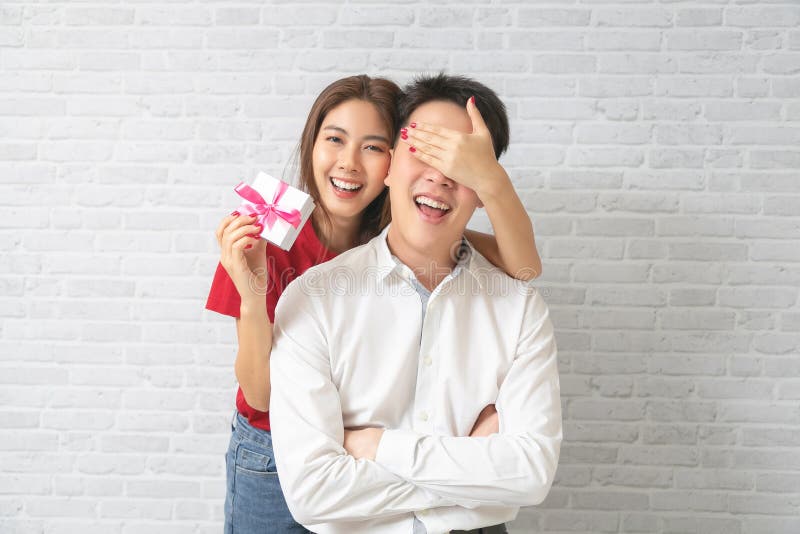 Young Man Receiving a Surprise Gift Box from Girlfriend at Home Stock