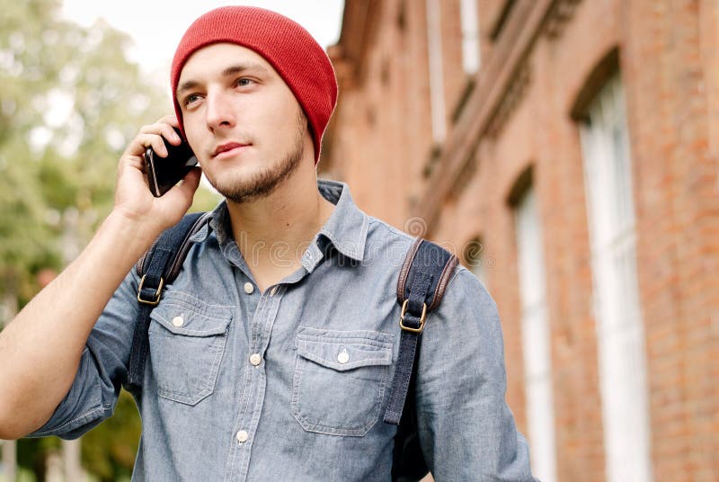 The young man with red cap calls on his cell phone. Caucasian, background.