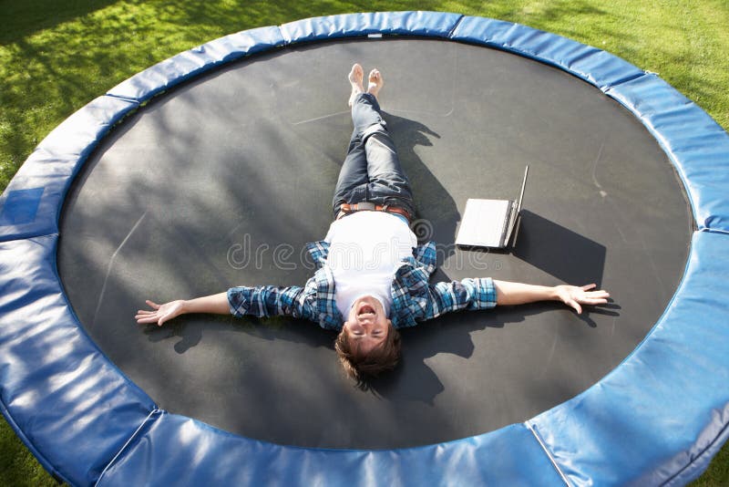 Young Man Relaxing On Trampoline With Laptop