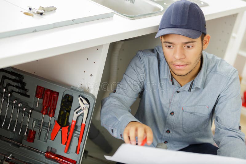 Young Man Repair Something Inside Kitchen Under Sink Stock