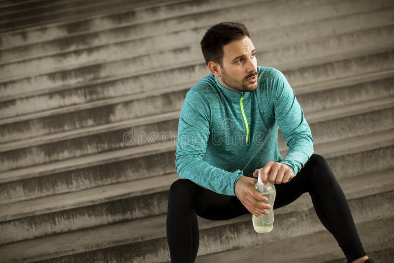 Young man resting during training with bottle of water stock photography