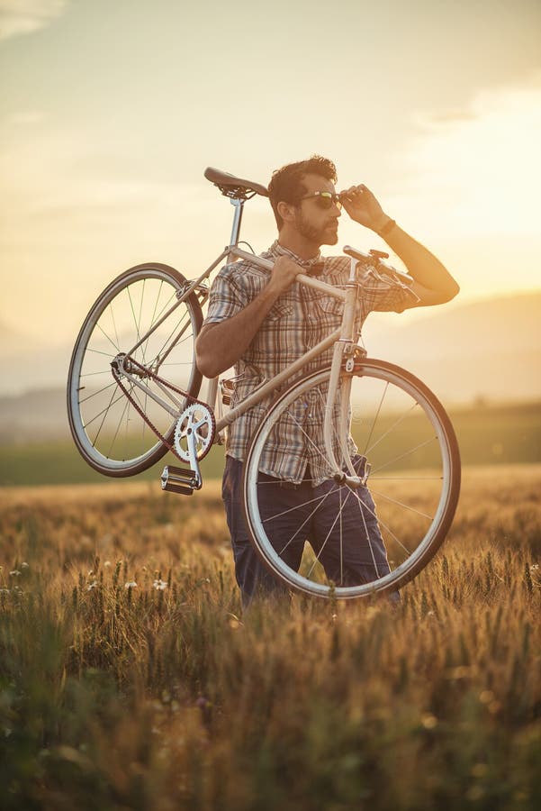 Young man with retro bicycle in sunset on the road, fashion photography on retro style with bike