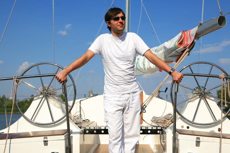 Young man on sailboat desk looks ahead.