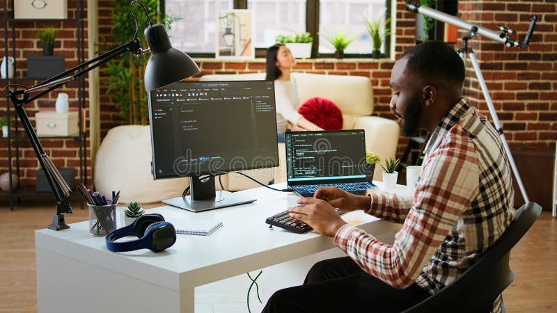 Young man seen programming software code on his laptop in a sleek home office stock photos