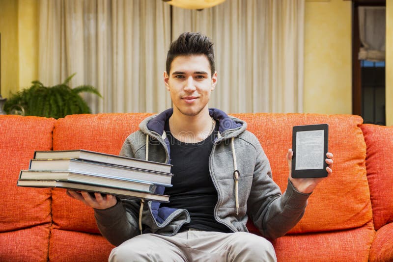 Young man showing difference between ebook reader and heavy books