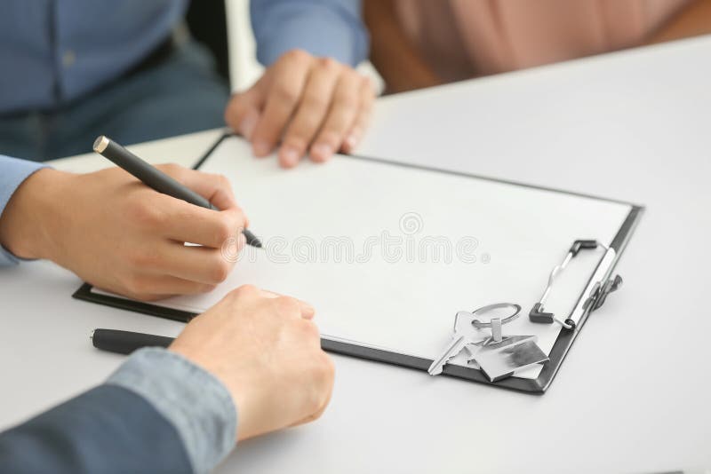 Young man signing a contract for buying house in office of estate agent stock photography Young man signing a contract for buying house in office of estate agent stock photography
