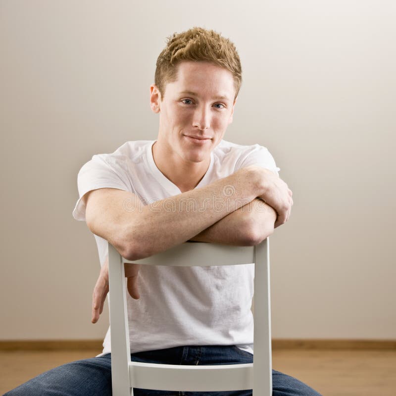 Young man sitting backwards in chair. 