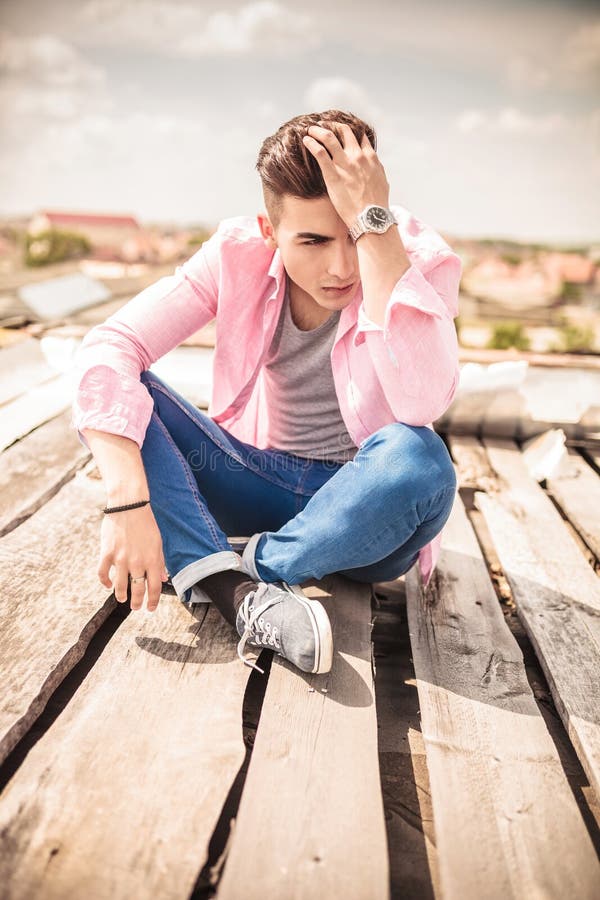 young man sitting fixing his hair serious outdoor picture 41025100