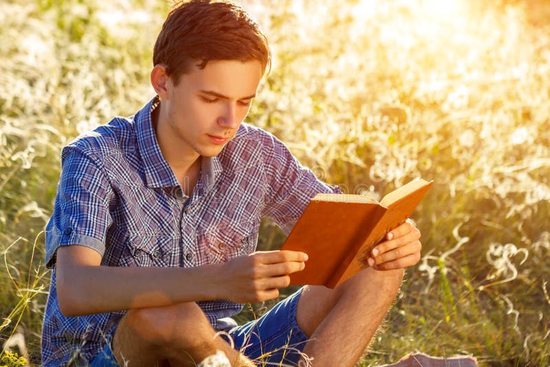 Young man sitting in nature reading a book stock photos Young man sitting in nature reading a book stock photos