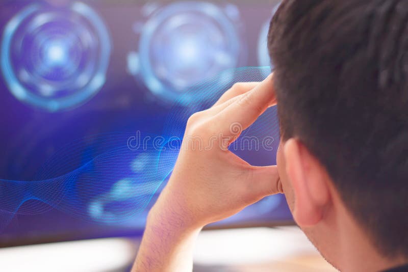 A young man sitting at office computer screen with futuristic sci fi IT digital interface elements and thinking royalty free stock images A young man sitting at office computer screen with futuristic sci fi IT digital interface elements and thinking royalty free stock images
