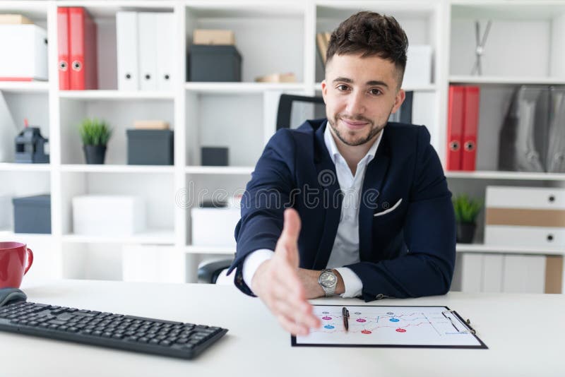 A Young Man Sitting In The Office At The Computer Table And