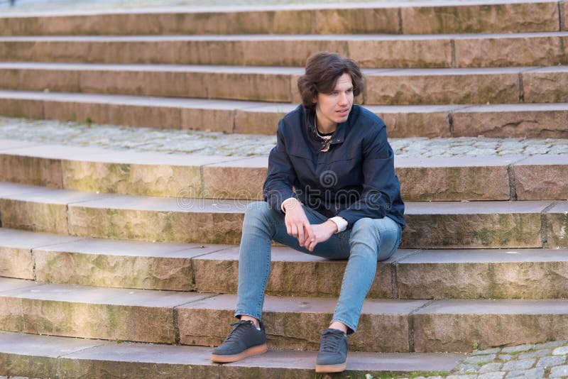 A young man is sitting on a stairs outdoors stock photography A young man is sitting on a stairs outdoors stock photography