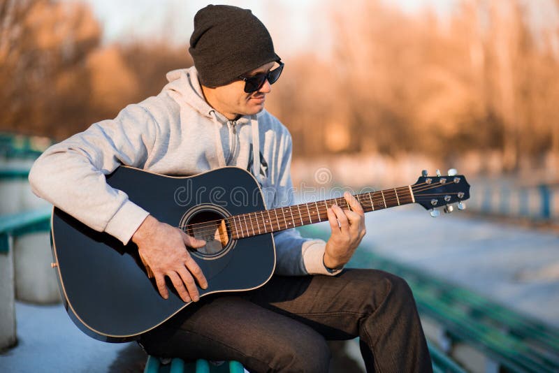 Young Man Sitting on Steps Playing Guitar and Singing Stock Photo