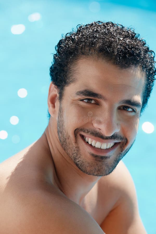 Pekný šťastný mladý hispánsky muž a relaxačné najbližšie zariadenie poskytujúce ubytovacie služby bazén.
