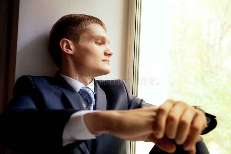 Young man sitting on windowsill