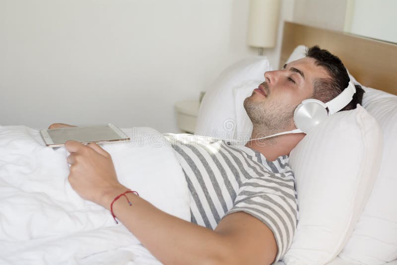 Young man sleeping in bed listening music stock photography Young man sleeping in bed listening music stock photography