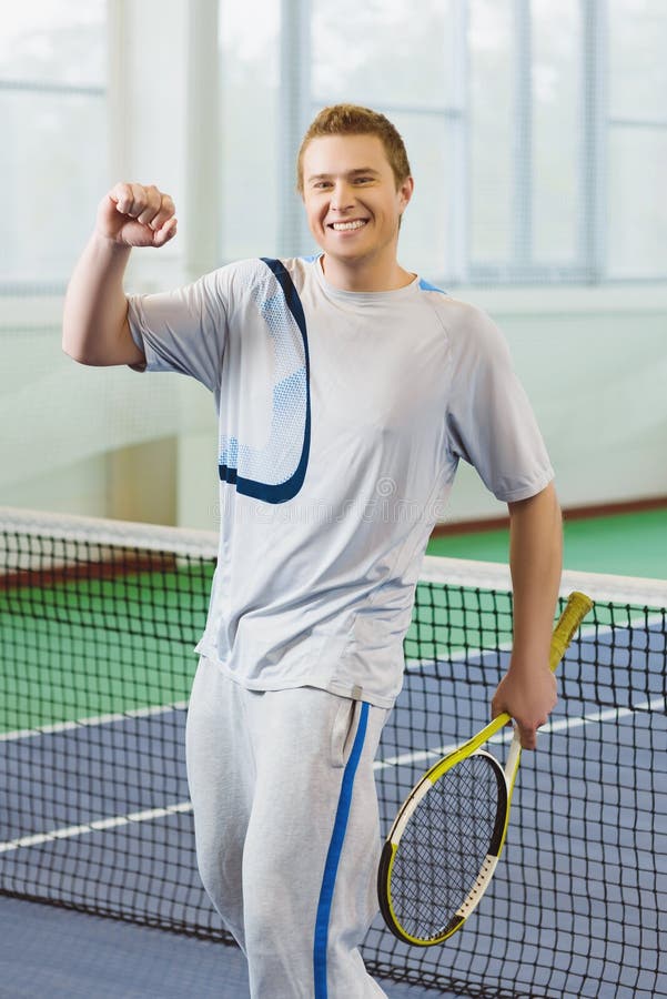 Young Man Smiling and Posing with Tennis Racket Indoor Stock Image