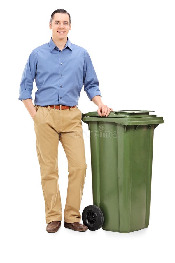 Young man standing by a large green trash can stock photo