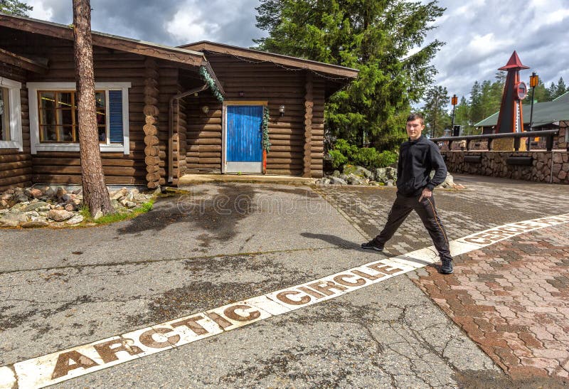 Young man standing on the line of the arctic circle in Rovaniemi