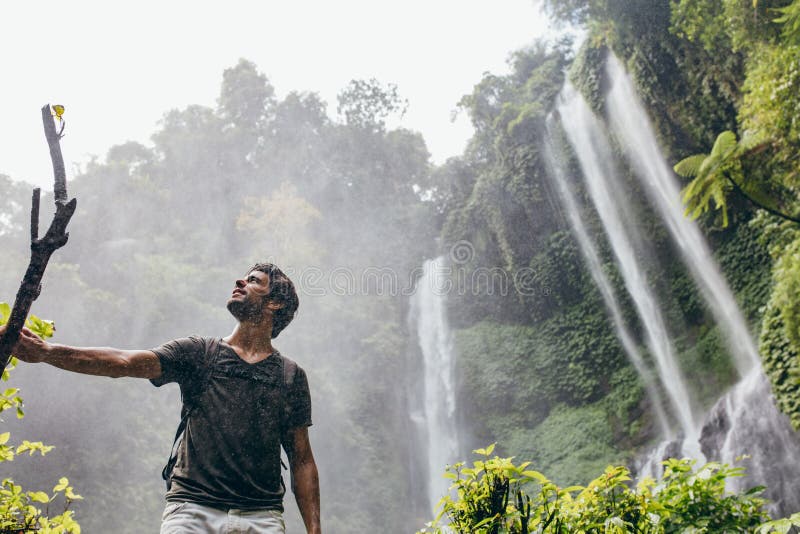 Young man standing near a waterfall in forest