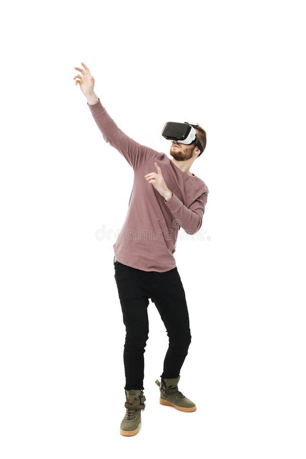 Young man standing in virtual reality glasses on white background. Cool thoughtful boy playing in visual reality glasses