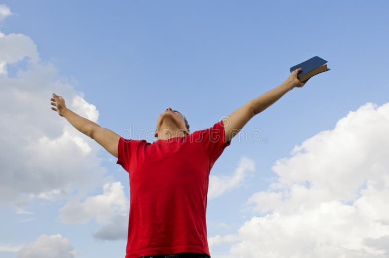 Young man staying with raised hands against blue sky