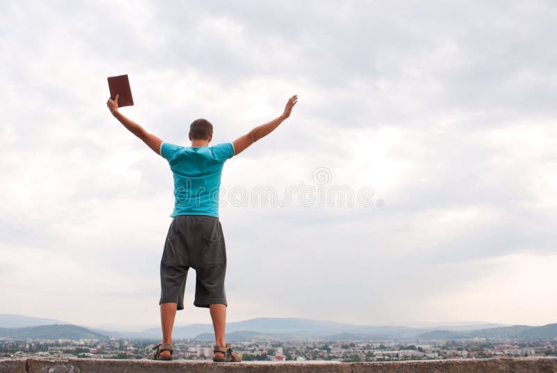 Young man staying with raised hands against blue sky