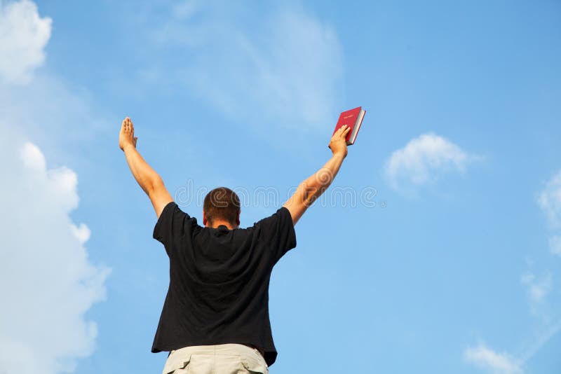 Young man staying with raised hands against blue sky