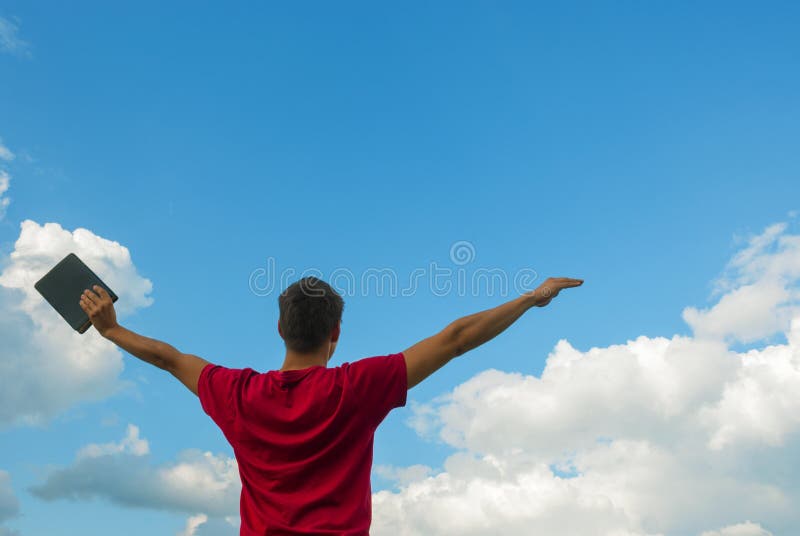 Young man staying with raised hands against blue sky