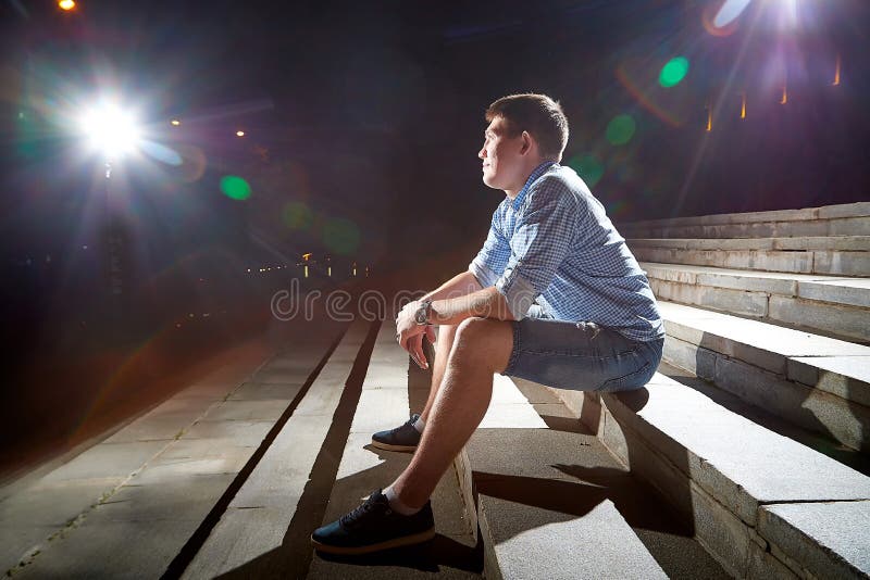 Young man on the steps of stairs in the night city street