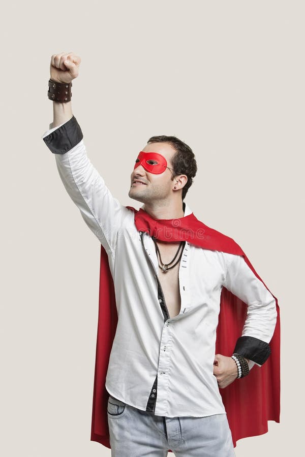 Young man in superhero costume standing against gray background stock images