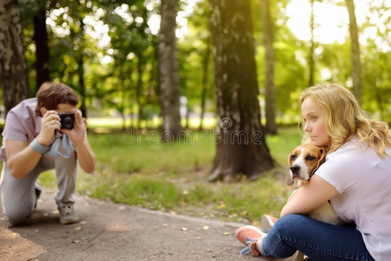 Young man take a shot beautiful woman with dog in sunny summer park. Date or walking royalty free stock image Young man take a shot beautiful woman with dog in sunny summer park. Date or walking royalty free stock image