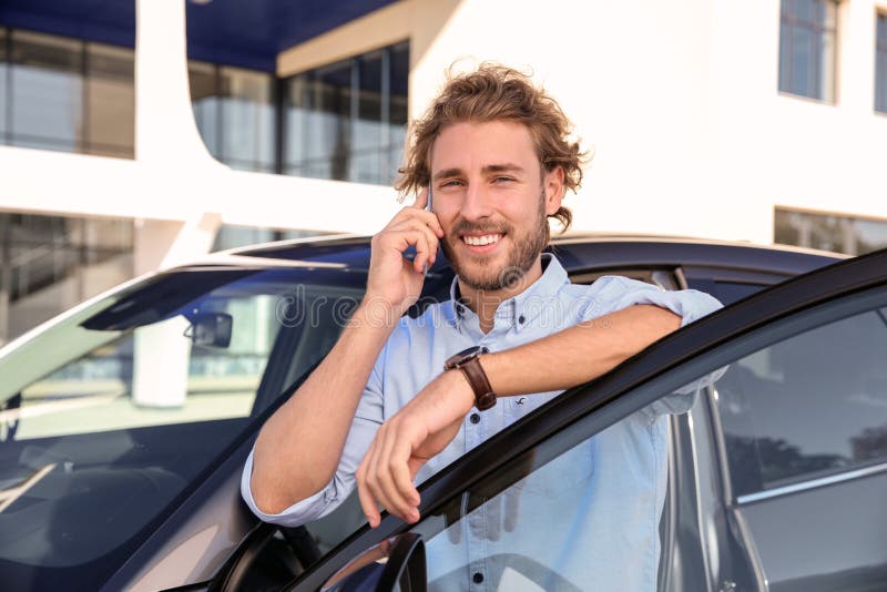 Young man talking on phone near modern car