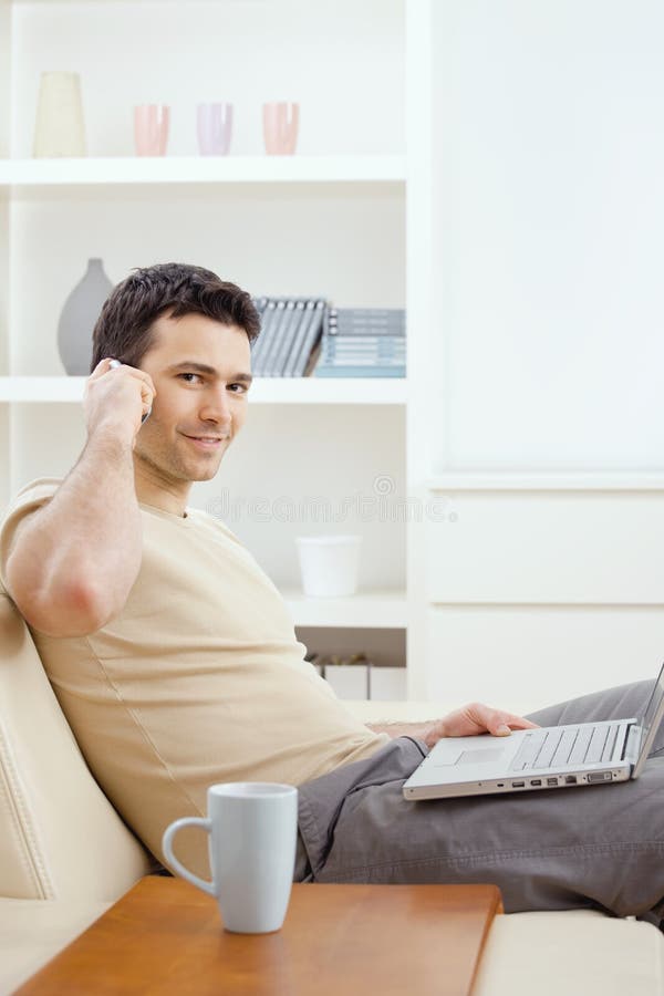 Young man sitting on sofa and teleworking from home. Young man sitting on sofa and teleworking from home.