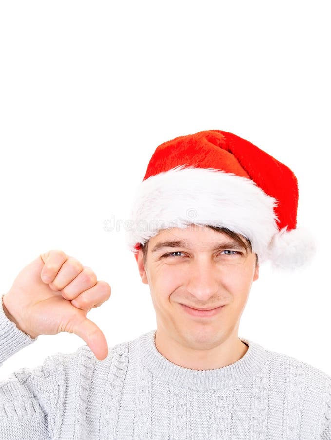 Unhappy Young Man in Santa Hat make Thumb Down on the White Background. Unhappy Young Man in Santa Hat make Thumb Down on the White Background