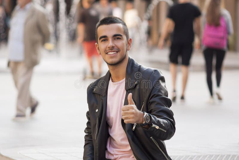 Young man thumbs up in the street and looking at camera royalty free stock images Young man thumbs up in the street and looking at camera royalty free stock images