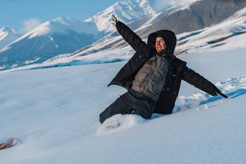 Young Man Tourist Sliding Down from Mountain in Winter Stock Photo