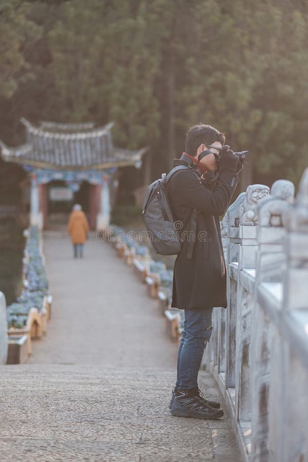 Young Man Traveler Traveling At Black Dragon Pool With Jade Dragon Snow Mountain Background, Landmark And Popular Spot For