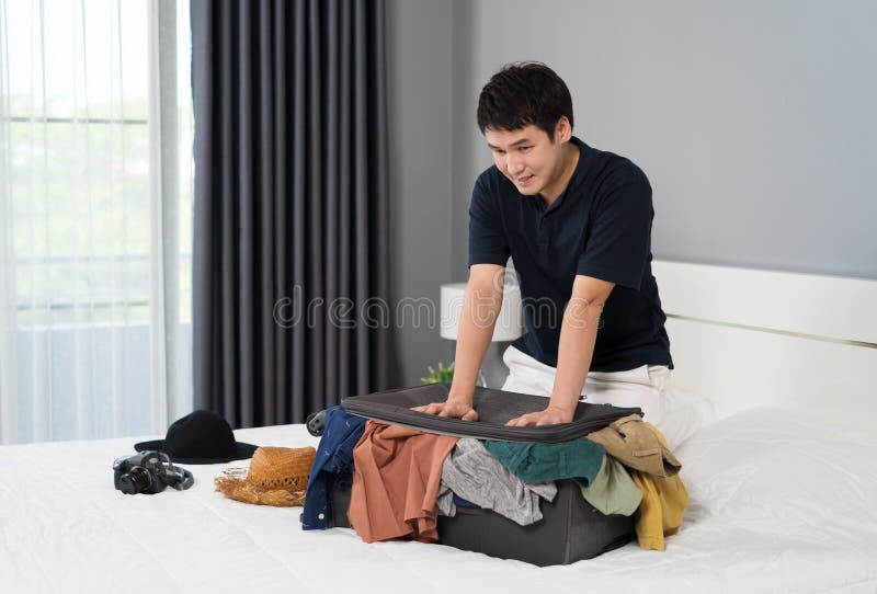 Man Trying To Close Overfilled Suitcase on His Bed Stock Image Image