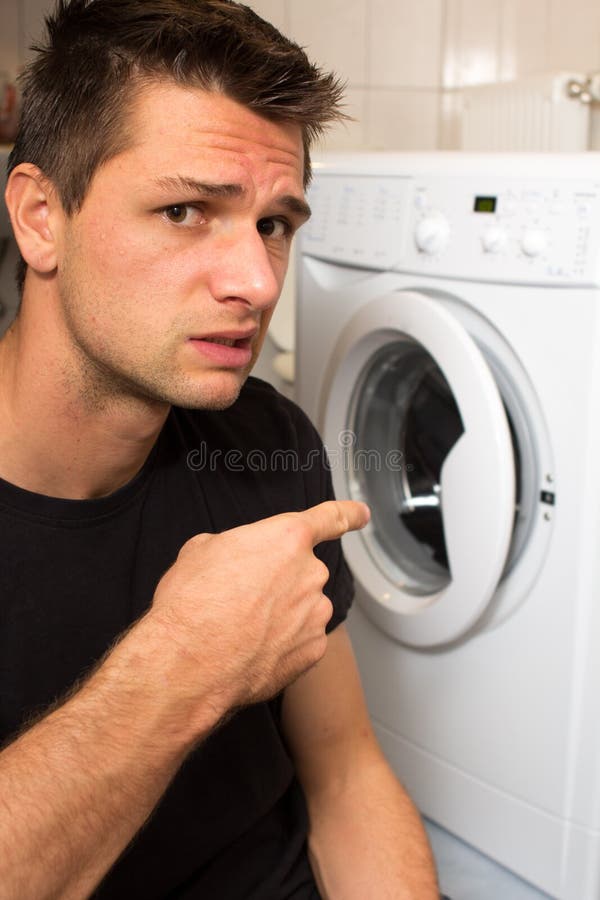 Young man unhappy with washing mashine stock photography