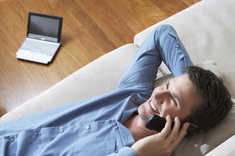 Young Man Using Cellphone On Sofa