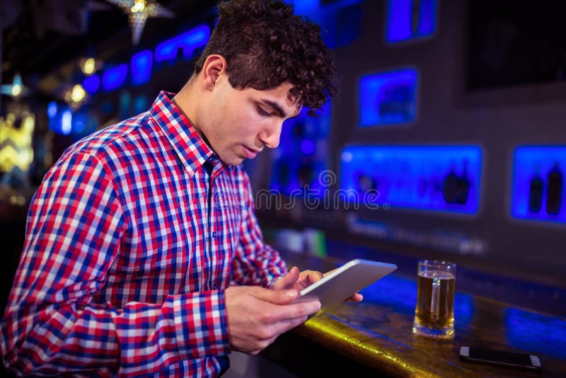Young man using digital tablet at bar counter royalty free stock photography