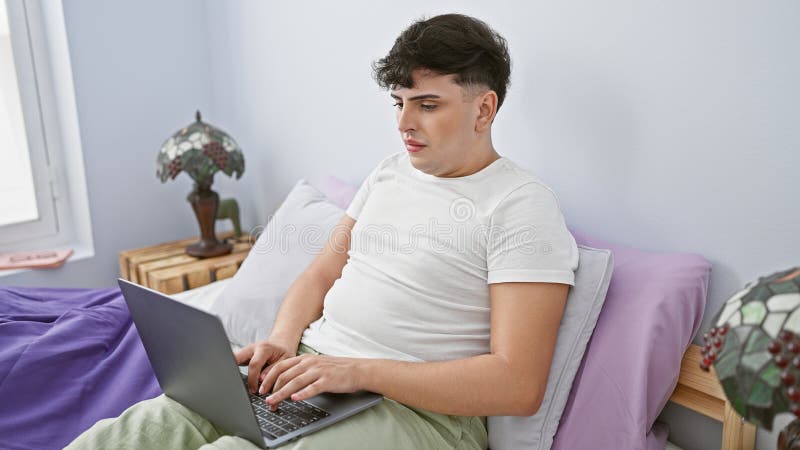 Young man using laptop in a casual bedroom setting, portraying modern indoor living royalty free stock photos