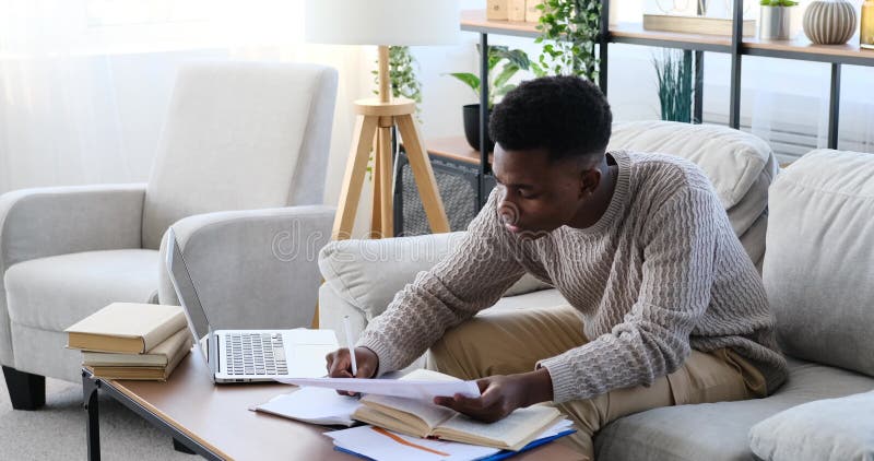 Young man using laptop and doing paperwork stock footage