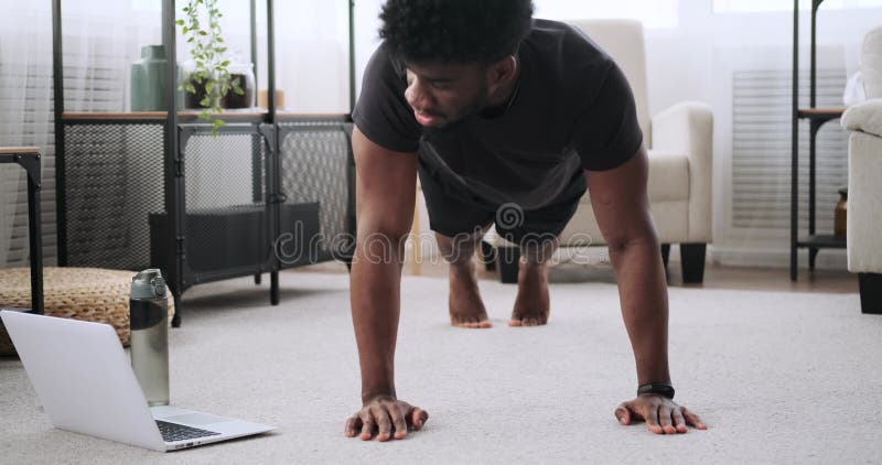 Young man using laptop while doing push up exercise stock video footage