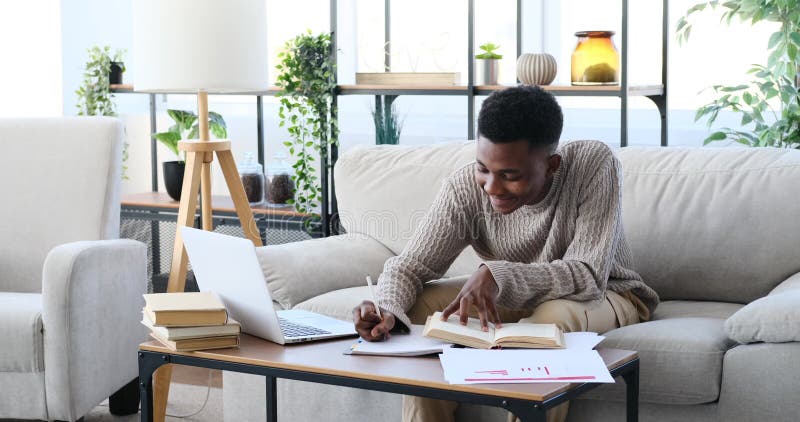 Young man using laptop and writing on paper stock video