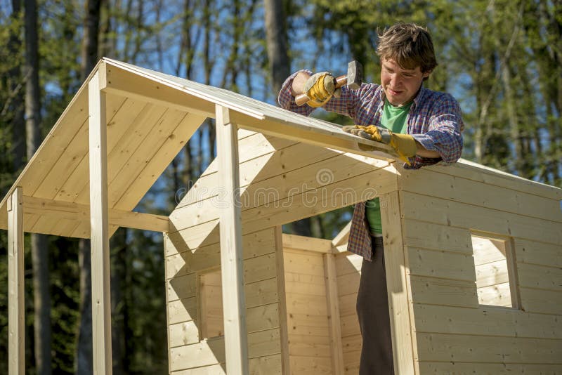Young man using a mallet to fix a nail into a roof of a wooden p royalty free stock photos