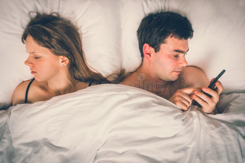 Young Man Using Mobile Phone, while His Wife Sleep at Night Stock Photo ... photo